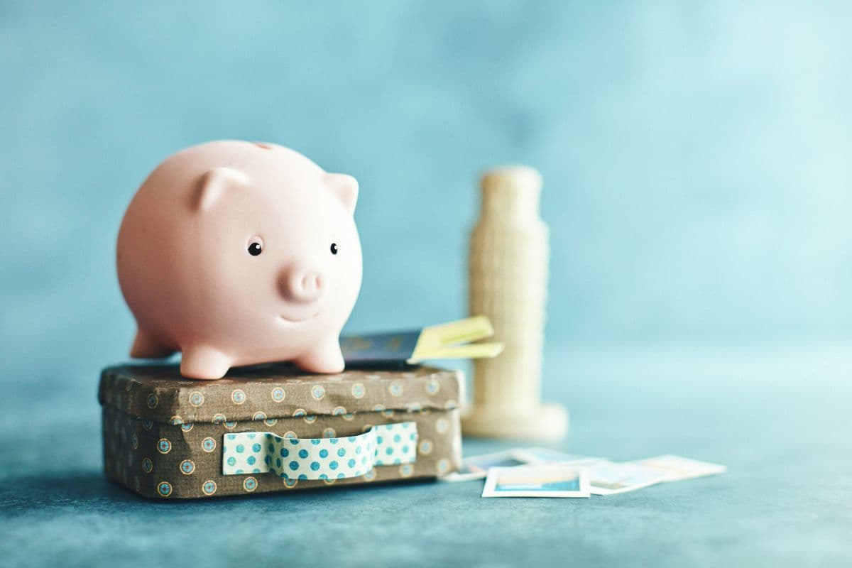 Piggy bank on luggage next to a plastic Tower of Pisa