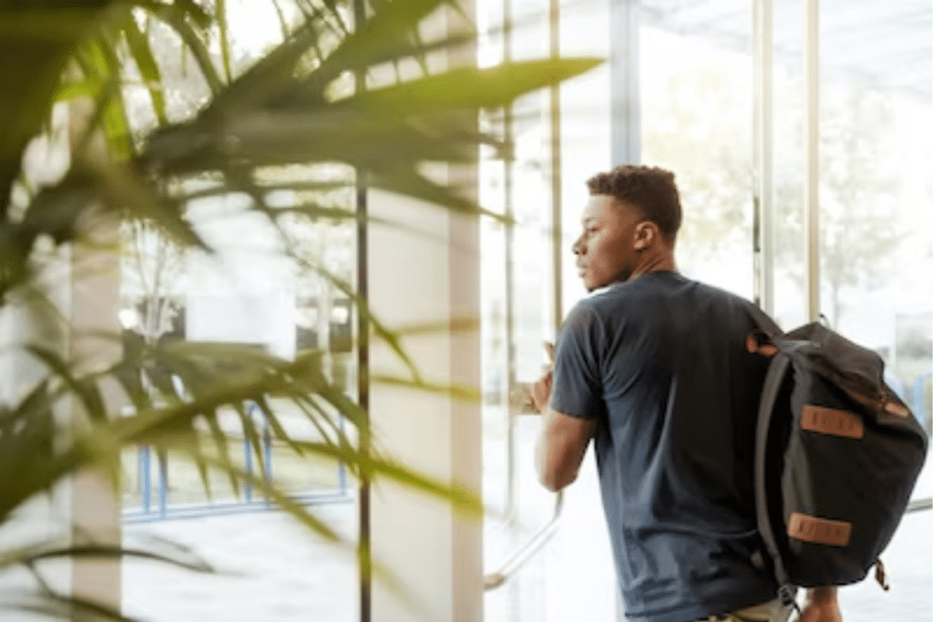 A boy with a backpack walks through a building, confidently navigating the interior with purpose and determination.